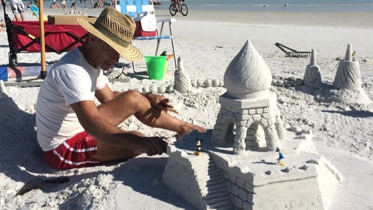 man building a sand castle on the beach